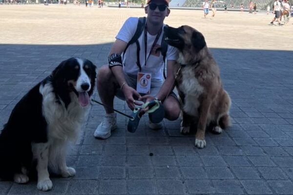 Joon Dog Tours guide with two dogs in front of the Louvre Pyramid in Paris