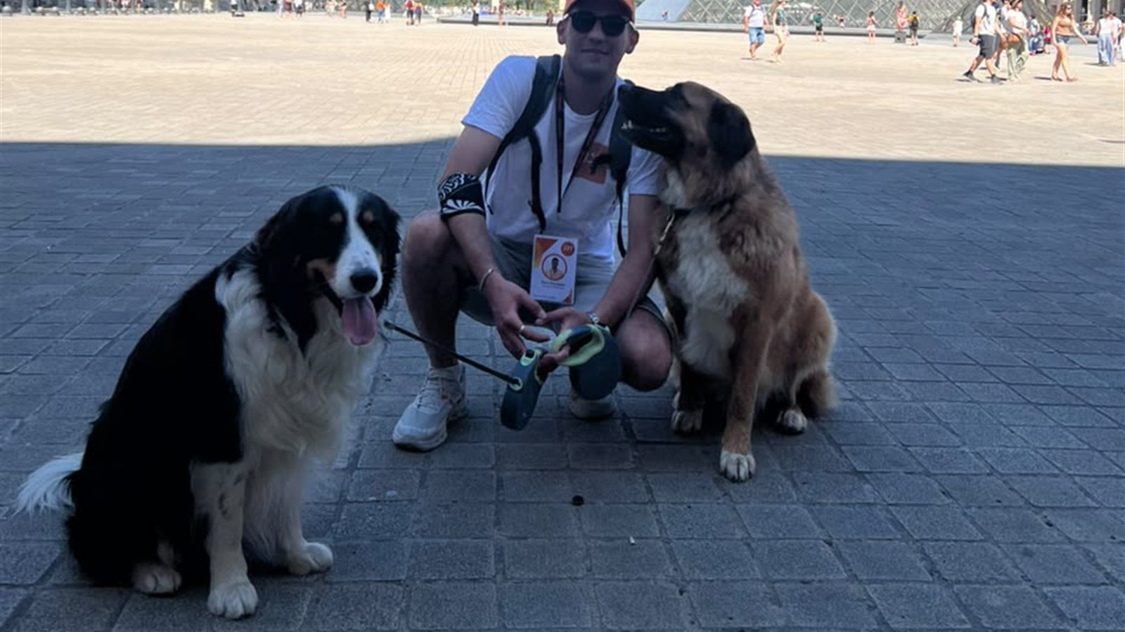 Joon Dog Tours guide with two dogs in front of the Louvre Pyramid in Paris